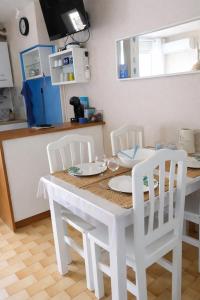 a kitchen with a white table and white chairs at MES VACANCES A LA MER studio 4 pers, parking privé, wifi, linges fournis, climatisation in La Grande Motte