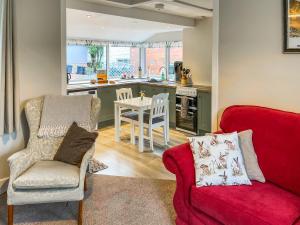 a living room with a red couch and a kitchen at Craigrannoch Cottage in Rockcliffe