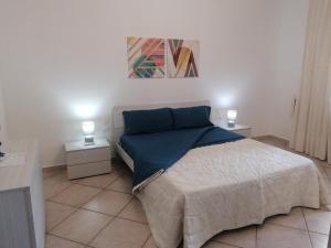 a bedroom with a bed with blue sheets and two lamps at Luminoso appartamento sul mare! in Piombino