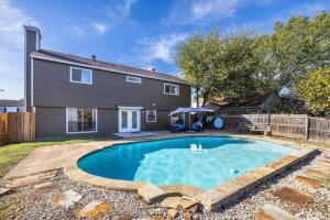 a swimming pool in front of a house at Spacious 4BR Home with Pool BBQ & Games in Grand Prairie