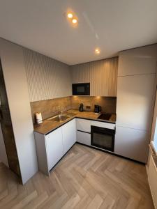 a kitchen with white cabinets and a sink at JAVA ESTATE apartment in Rēzekne
