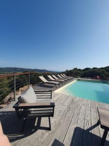 a pool with lounge chairs next to a wooden deck at Villa Cocooning, Piscine privative à Figari in Figari