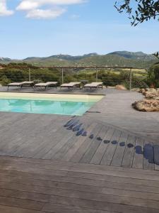 a swimming pool with tables and benches next to it at Villa Cocooning, Piscine privative à Figari in Figari