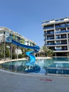 a large swimming pool with a blue slide next to a building at Modern, Pool with slide,150m to beach in Alanya