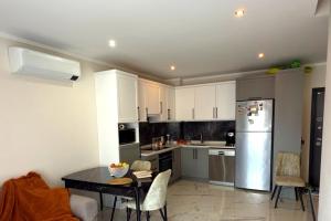 a kitchen with white cabinets and a table and a refrigerator at Modern, Pool with slide,150m to beach in Alanya