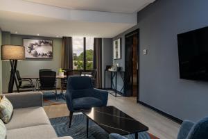 a living room with a couch and chairs and a tv at Radisson Blu Hotel Lusaka in Lusaka