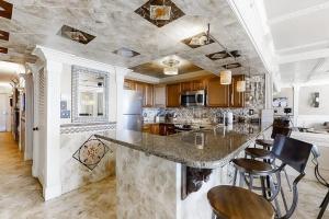 a kitchen with a large marble counter and stools at Pelican Beach Resort 1502 in Destin +36 photos