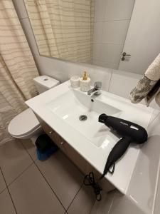 a bathroom with a white sink with a black hair dryer on it at Ivan Suite More than accommodation an experience in Santiago +10 photos