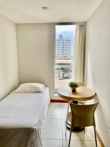 a bedroom with a bed and a table and a window at Sumatra Hotel e Centro de Convenções in Londrina +56 photos