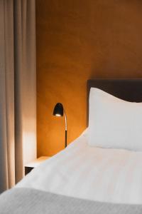 a bed with a white pillow and a lamp at Hótel Vesturland in Borgarnes