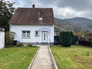 a small white house with a grassy yard at Ferienhaus mit Trifelsblick in Annweiler am Trifels