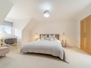 a white bedroom with a bed and a chair at Springbank in Brodick