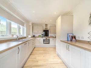 a kitchen with white cabinets and a large window at Springbank in Brodick +9 photos