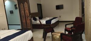 a hotel room with two beds and chairs and a tv at Shree ji palace hotel in Udaipur
