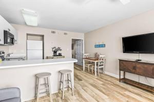 a kitchen and living room with a bar and a flat screen tv at Tropical Isle #205 in Fort Walton Beach