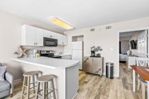 a white kitchen with a counter and stools at Tropical Isle #205 in Fort Walton Beach