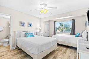 a white bedroom with two beds and a window at Tropical Isle #205 in Fort Walton Beach +10 photos