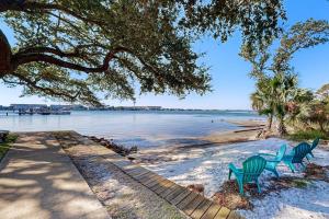 two green chairs sitting on the beach under a tree at Pirates Bay B314 in Fort Walton Beach