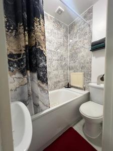 a bathroom with a toilet and a tub and a sink at Crescent Apartment - Two bedroom in Goodmayes
