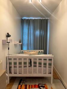 a white crib in a room with a window at Crescent Apartment - Two bedroom in Goodmayes