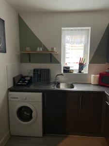 a kitchen with a sink and a washing machine at Crescent Apartment - Two bedroom in Goodmayes +6 photos