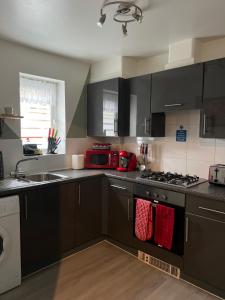 a kitchen with black cabinets and red towels at Crescent Apartment - Two bedroom in Goodmayes