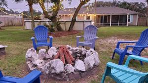 three blue chairs around a fire pit in a yard at Poolside Palms Paradise in Navarre