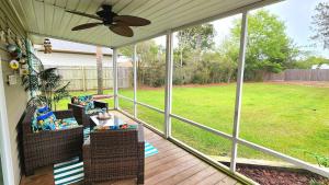 a screened porch with chairs and a ceiling fan at Poolside Palms Paradise in Navarre