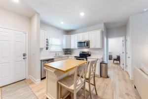 a kitchen with white cabinets and a wooden table at Windmark - Sea Grove Guesthouse in Saint Joe Beach