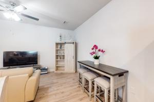 a living room with a table and chairs and a television at Windmark - Sea Grove Guesthouse in Saint Joe Beach