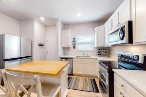 a kitchen with white cabinets and a wooden table at Windmark - Sea Grove Guesthouse in Saint Joe Beach
