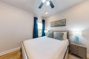 a bedroom with a white bed and a ceiling fan at Windmark - Sea Grove Guesthouse in Saint Joe Beach