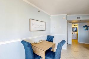 a dining room with a wooden table and blue chairs at Sundunes 121 in Navarre +22 photos