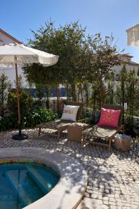 a patio with chairs and an umbrella and a pool at Estoril Boutique Hotel - Adults Only in Estoril