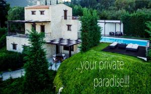 a house on a grassy hill with a swimming pool at Exensian Villas & Suites in Marathias
