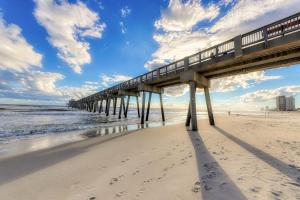 a pier on a beach with footprints in the sand at Seychelles Beach Resort 2004 in Panama City Beach