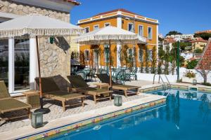 a pool with chairs and umbrellas next to a house at Estoril Boutique Hotel - Adults Only in Estoril