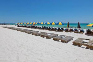 a row of lounge chairs and umbrellas on a beach at Seychelles Beach Resort 2001 in Panama City Beach