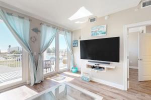 a living room with a flat screen tv and a large window at Tranquil Harbour #211 in Mexico Beach
