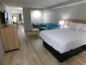 a hotel room with a bed and a television and chairs at Days Inn by Wyndham Effingham in Effingham