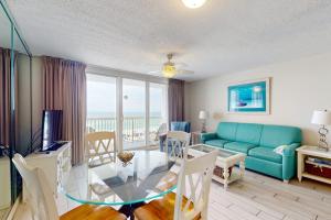 a living room with a blue couch and a glass table at Pelican Beach Resort 502 in Destin