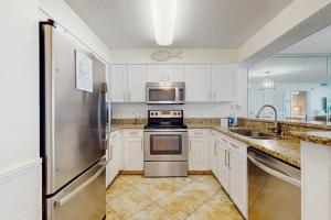 a kitchen with white cabinets and a stainless steel refrigerator at Pelican Beach Resort 415 in Destin
