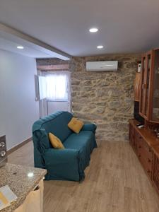 a living room with a blue couch and a stone wall at Casa da Miquinhas II in Ponte da Barca