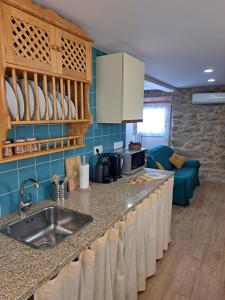 a kitchen with a sink and a living room at Casa da Miquinhas II in Ponte da Barca