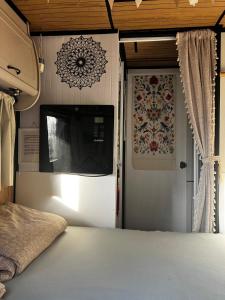 a bedroom with a tv on the wall next to a door at Glamping Karavan u Konopiště in Chrášťany