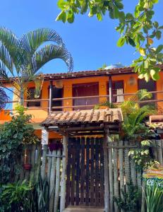 an orange house with a wooden fence in front of it at Pousada Clara Caraíva in Caraíva