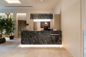 a woman sitting at a reception desk in a lobby at UNAHOTELS Villa dei Platani Foligno in Foligno
