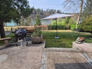 a grill and an umbrella in a park at Zbilje Lake house in Medvode