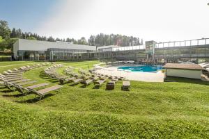 a large building with a pool and lounge chairs at Hotel und Therme NOVA in Köflach