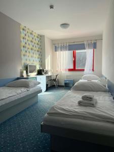 a bedroom with two beds and a desk with a computer at Hotel Galaxie in Zlín